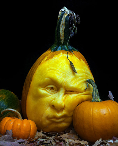 A pumpkin is leaning its face against a smaller pumpkin.